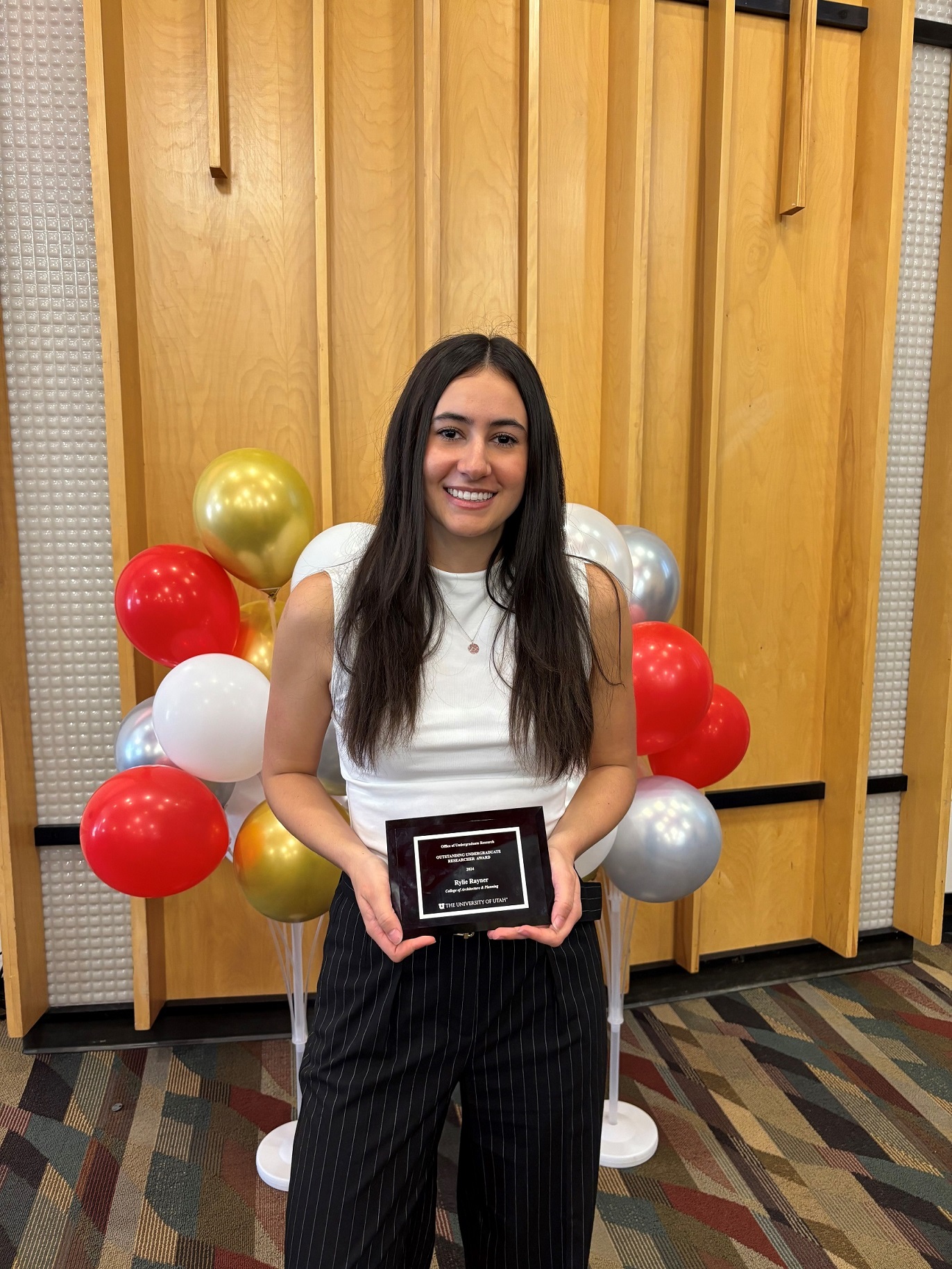 Student Rylie Rayner holds an award for Outstanding Undergraduate Research